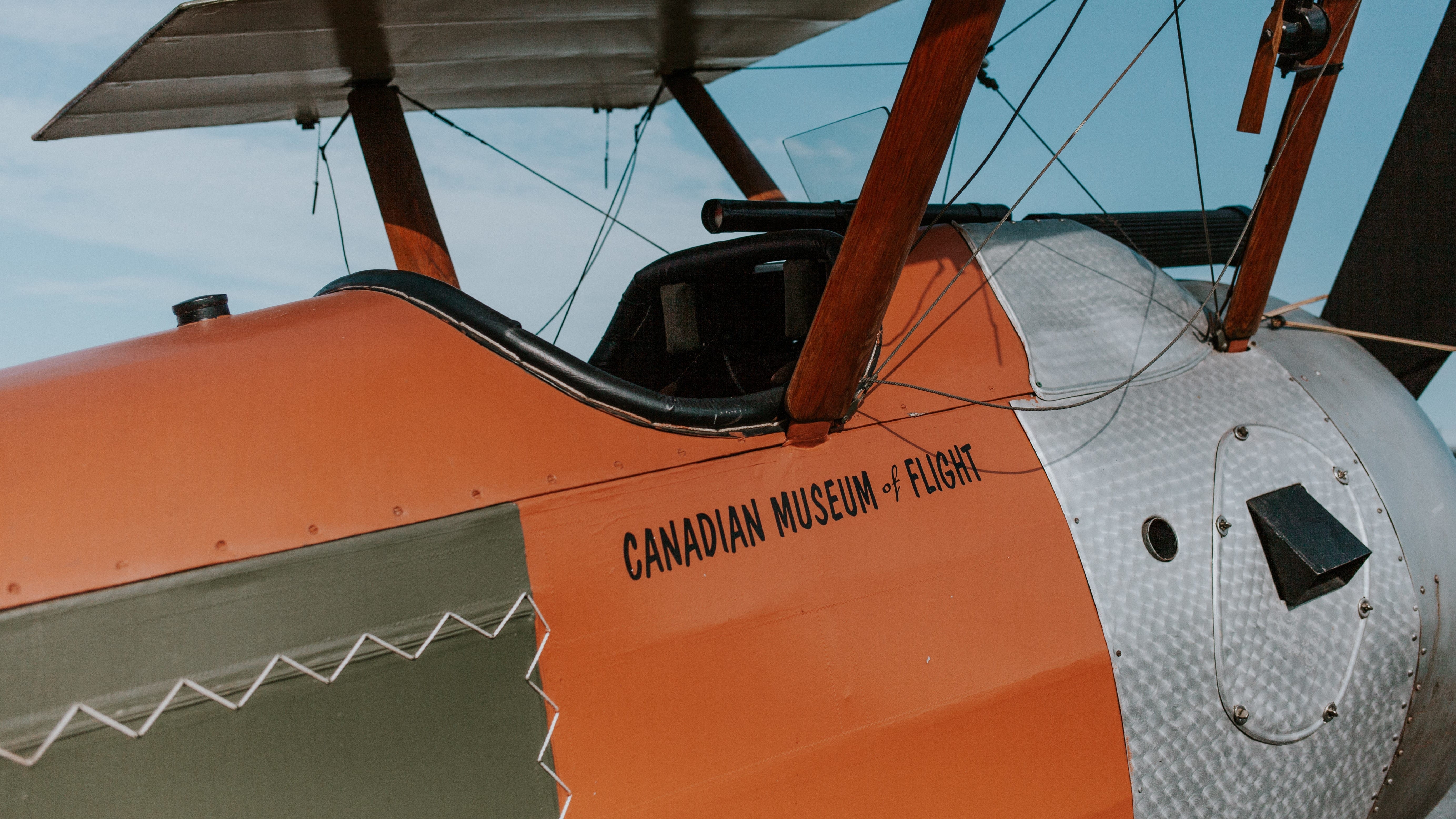 Close-up of a vintage biplane with "Canadian Museum of Flight" written on the fuselage, showing wooden struts and part of the cockpit.