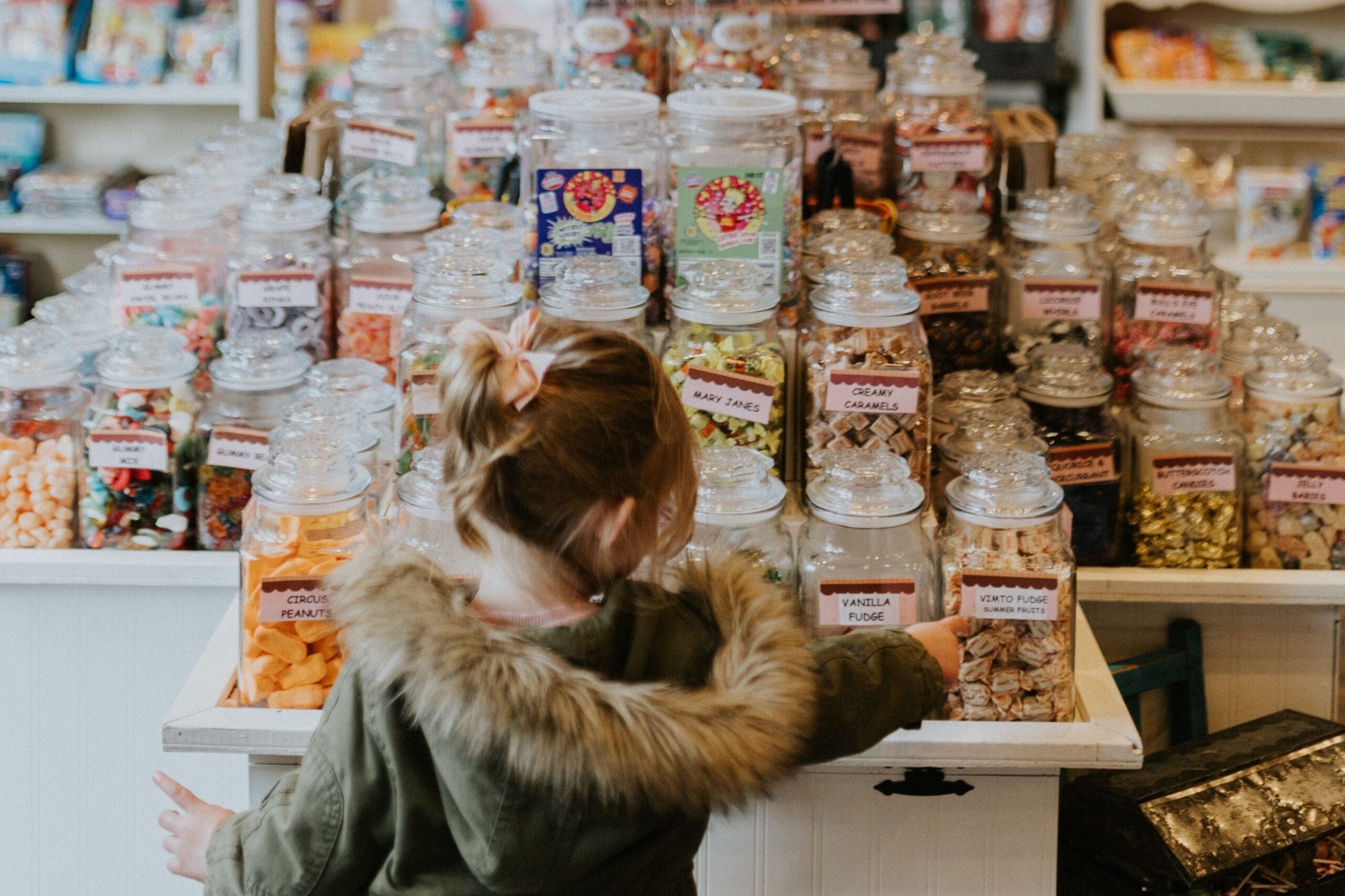 A young girl reaching toward jars of candy and fudge at Into Chocolate, a confectionery shop on Glover Road in Fort Langley, BC.